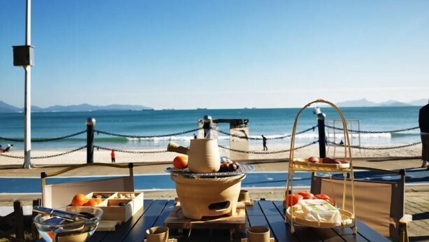 A beachside dining setup with a grill, fruits, and a view of the ocean. - Shenzhen Xiyong Resort (Shenzhen)