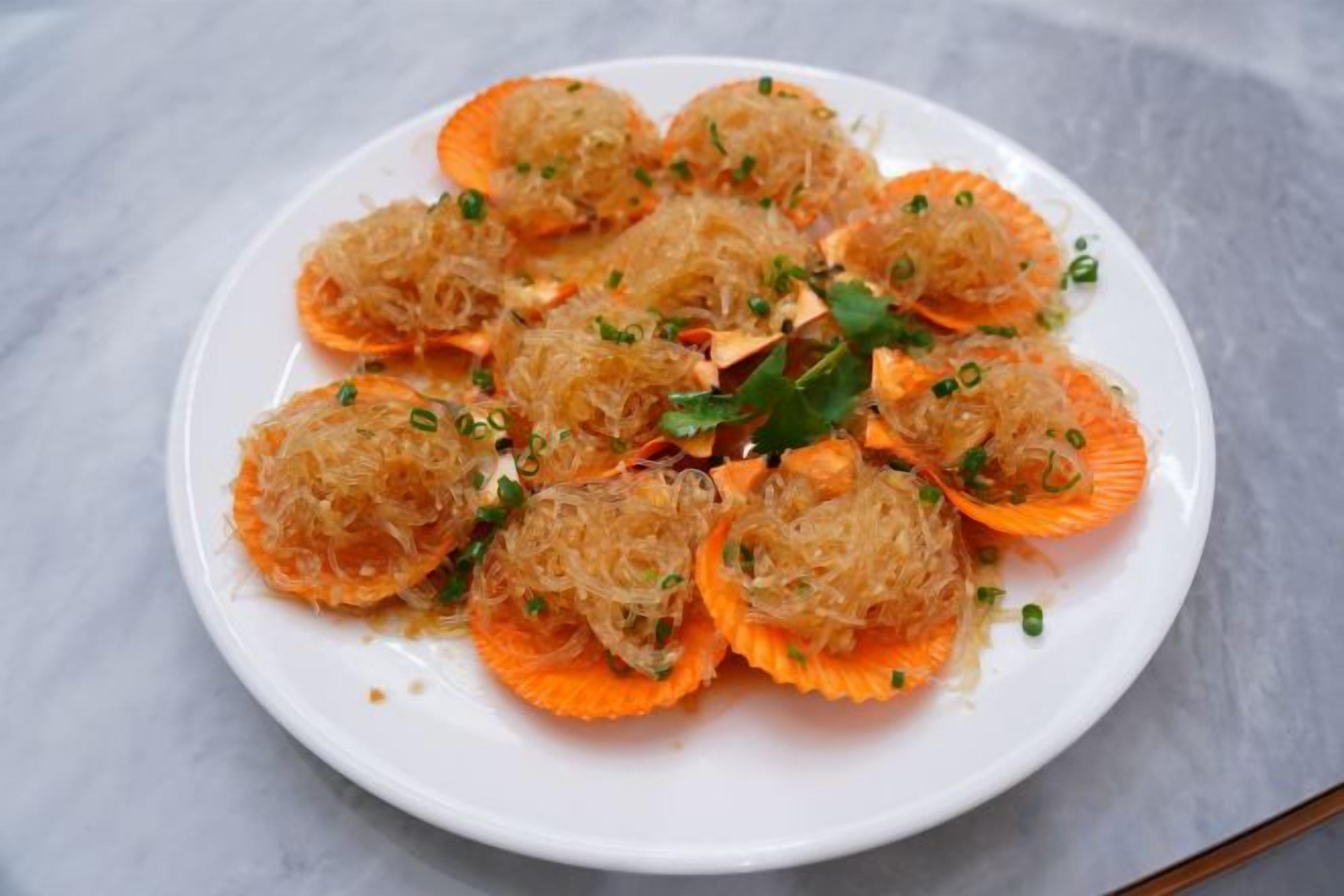 Un plato de comida con esferas y cáscaras anaranjadas, adornado con hierbas verdes.