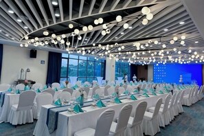 Une salle de conférence avec des tables rondes, des chaises blanches et un fond bleu.