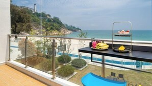 A balcony with a view of the sea, a pool, and a dining area with fruit. - Shenzhen Xiyong Resort (Shenzhen)
