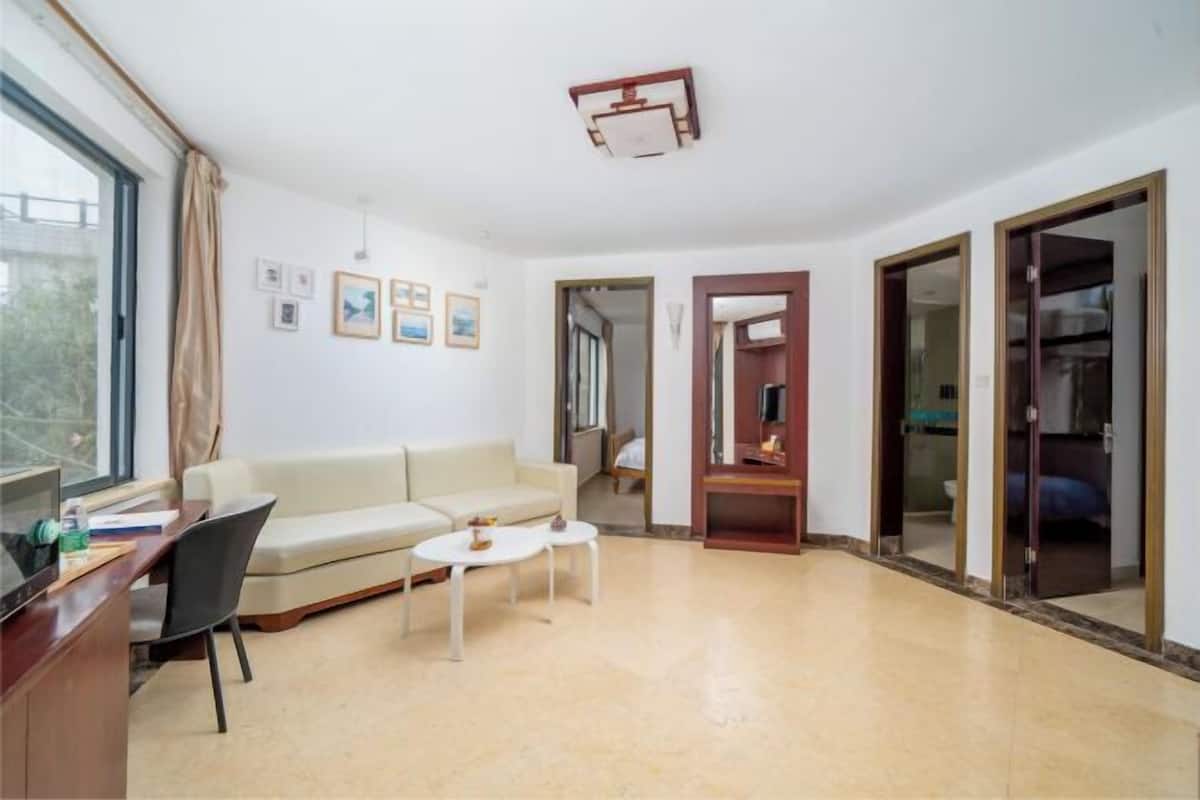 Una sala de estar moderna con un sofá, dos mesitas y una televisión, además de un ventanal.