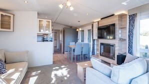 A modern living room with a sofa, a fireplace, and a dining area with a table and chairs.