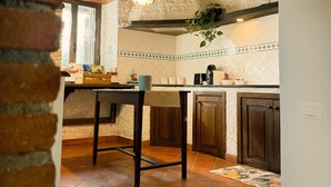 A rustic kitchen with exposed beams, a hanging plant, and a tiled floor. - Mondifeso Chalet (Etna+vineyard+jacuzzi) (Pedara)