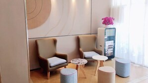 A modern lobby with two armchairs, a small round table, ottomans, and a vending machine. - Yuejia Hotel (Shanghai Qingpu District Sports Center Qingpu New City Metro Station Branch) (Shanghai)