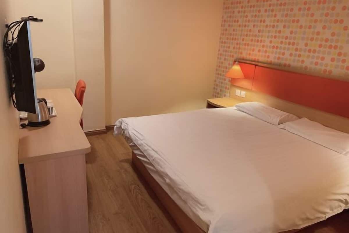 Habitación de hotel con cama, escritorio, silla, lámpara y pared con estampado de lunares.