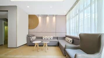 Uma sala de estar moderna com sofá modular, mesa de centro redonda e uma grande janela que ilumina naturalmente o ambiente.