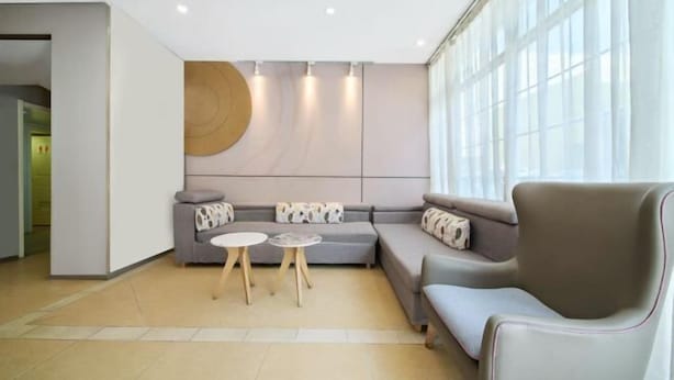 A modern living room with a grey sofa, two small round tables, and a large window with sheer curtains. - Yuejia Hotel (Shanghai Qingpu District Sports Center Qingpu New City Metro Station Branch) (Shanghai)