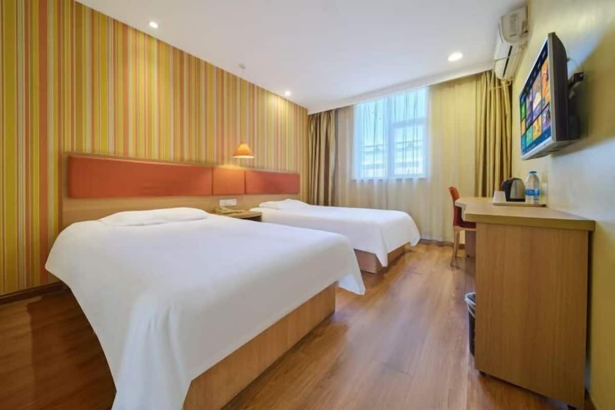Una habitación de hotel con dos camas, un escritorio, un televisor y una ventana.