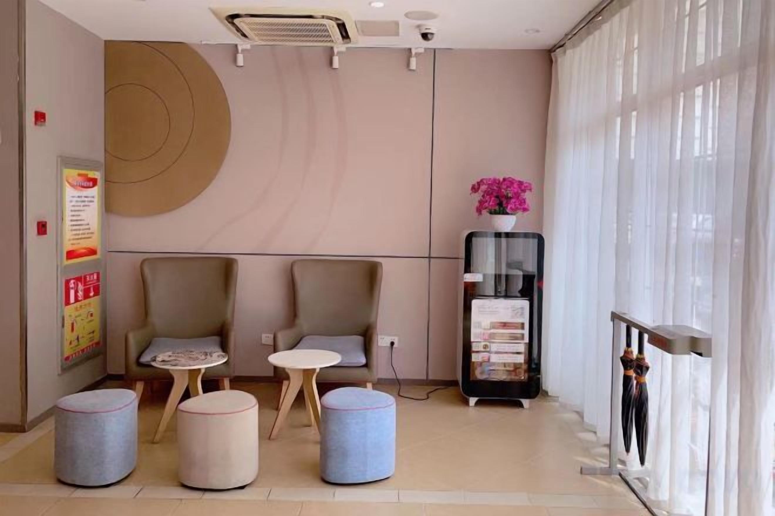 Um saguão de hotel com áreas de estar, um balcão de recepção e uma janela grande.