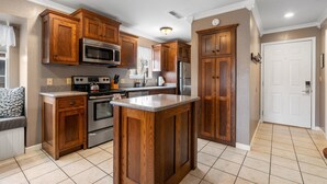 A kitchen with wooden cabinets, stainless steel appliances, and a tiled floor.