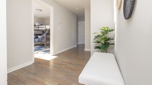 Un pasillo con piso de madera, un banco y una planta en maceta.