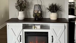 Una sala de estar moderna con una televisión de pantalla plana montada sobre un mueble blanco que incluye una chimenea.