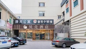 Un hotel con un cartel que indica que es un hotel público y cuenta con un restaurante. Hay coches aparcados en la calle.