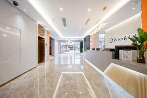 Un hall d’hôtel avec un sol en marbre, un comptoir d’accueil et une enseigne indiquant « Bush Hotel ».
