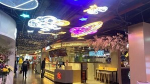 Un espacio interior moderno con mostrador de comida, zona de estar e iluminación decorativa en el techo.