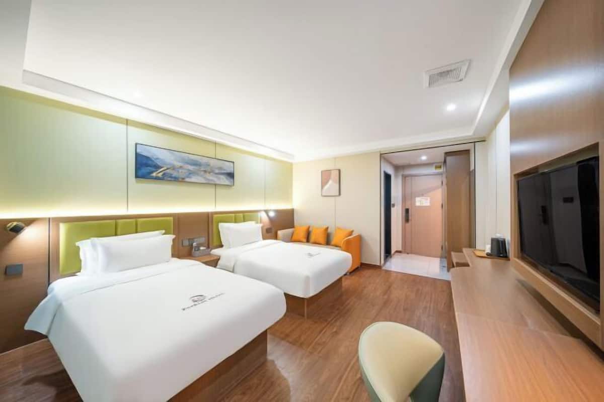 A hotel room with two beds, a TV, and a painting on the wall.