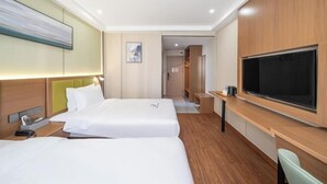 Una habitación de hotel con dos camas, televisión, escritorio y un cuadro en la pared.