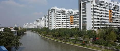 Une rivière longe une rangée d’immeubles résidentiels à plusieurs étages, dotés de balcons.