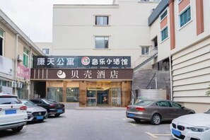 L’entrée d’un hôtel, avec un panneau indicateur, un parking et des bâtiments adjacents.