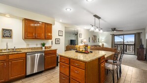 A spacious kitchen with wooden cabinets, a stainless steel dishwasher, and a granite countertop. - Pointe Royale Resort | Golf, Indoor Pool & More (Branson)