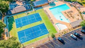 An aerial view of a sports complex with multiple tennis courts, a swimming pool, and a parking area. - Pointe Royale Resort | Golf, Indoor Pool & More (Branson)