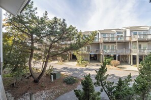 Un edificio de varios pisos con balcones, un paseo cubierto y una zona de estacionamiento.