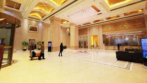 A spacious lobby with a high ceiling, a reception desk, and a seating area.