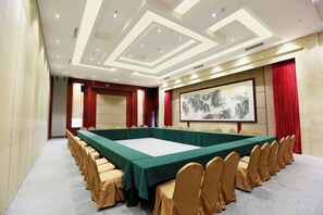 A conference room with a long table, chairs, and a large painting on the wall. - Huidu Hotel (Longmen)