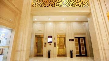 A hotel lobby with a grand entrance, double doors, and a patterned ceiling.