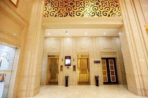 Um hall de hotel com entrada imponente, portas duplas e teto trabalhado.