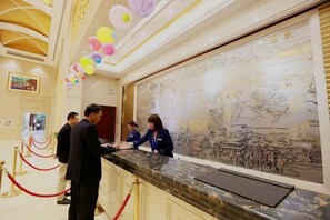 Un mostrador de recepción con un gran mural, una barrera de cuerda roja y un techo con adornos colgantes.