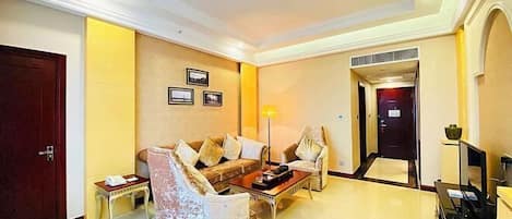A hotel lobby with a seating area, a reception desk, and a door leading to another room.