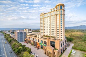 A multi-story hotel with a central courtyard, surrounded by greenery and a clear sky. - Huidu Hotel (Longmen)