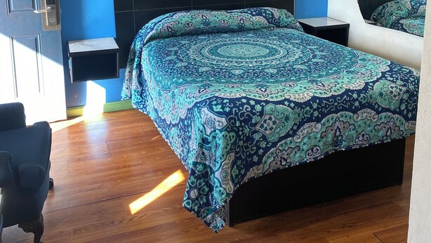 A bedroom with a bed, a nightstand, a chair, and a picture on the wall.