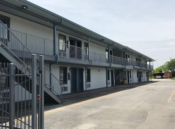 Un motel composé d’un bâtiment à deux étages, d’un espace de stationnement couvert et d’une entrée sécurisée par un portail.