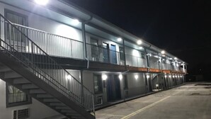 A multi-story motel with a central staircase, balconies, and a parking lot.