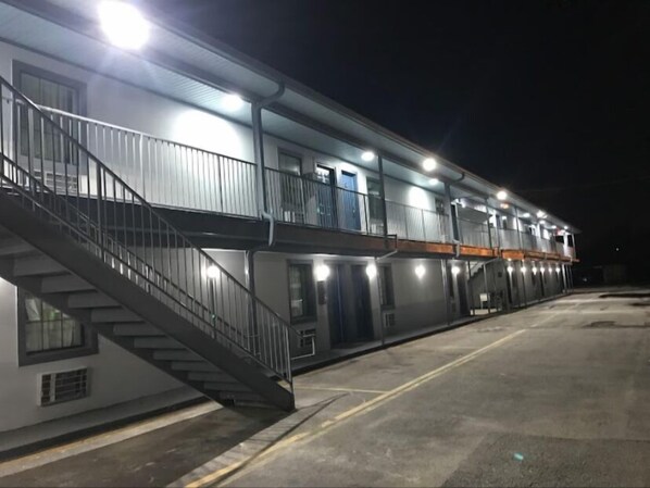 A multi-story motel with a central staircase, balconies, and a parking lot. - Jacks motel  (New Orleans)