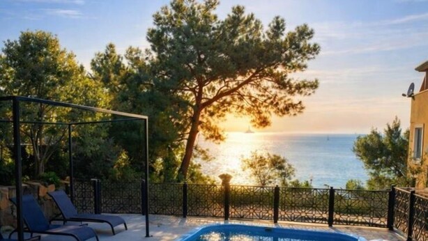 Ein Poolbereich mit Blick aufs Meer, Liegestühle und ein Tisch mit gemustertem Tuch.