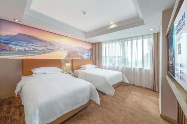 A hotel room with two beds, a large mural on the wall, and a view of a cityscape through the window. - Vienna Hotel (Qingyuan City Plaza Lianjiang Road) (Qingyuan)