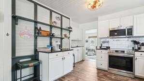 Una cocina moderna con armarios blancos, electrodomésticos de acero inoxidable y suelo de madera.