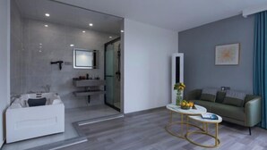 Uma sala de estar moderna com sofá, mesa de centro e divisória de vidro para um banheiro.