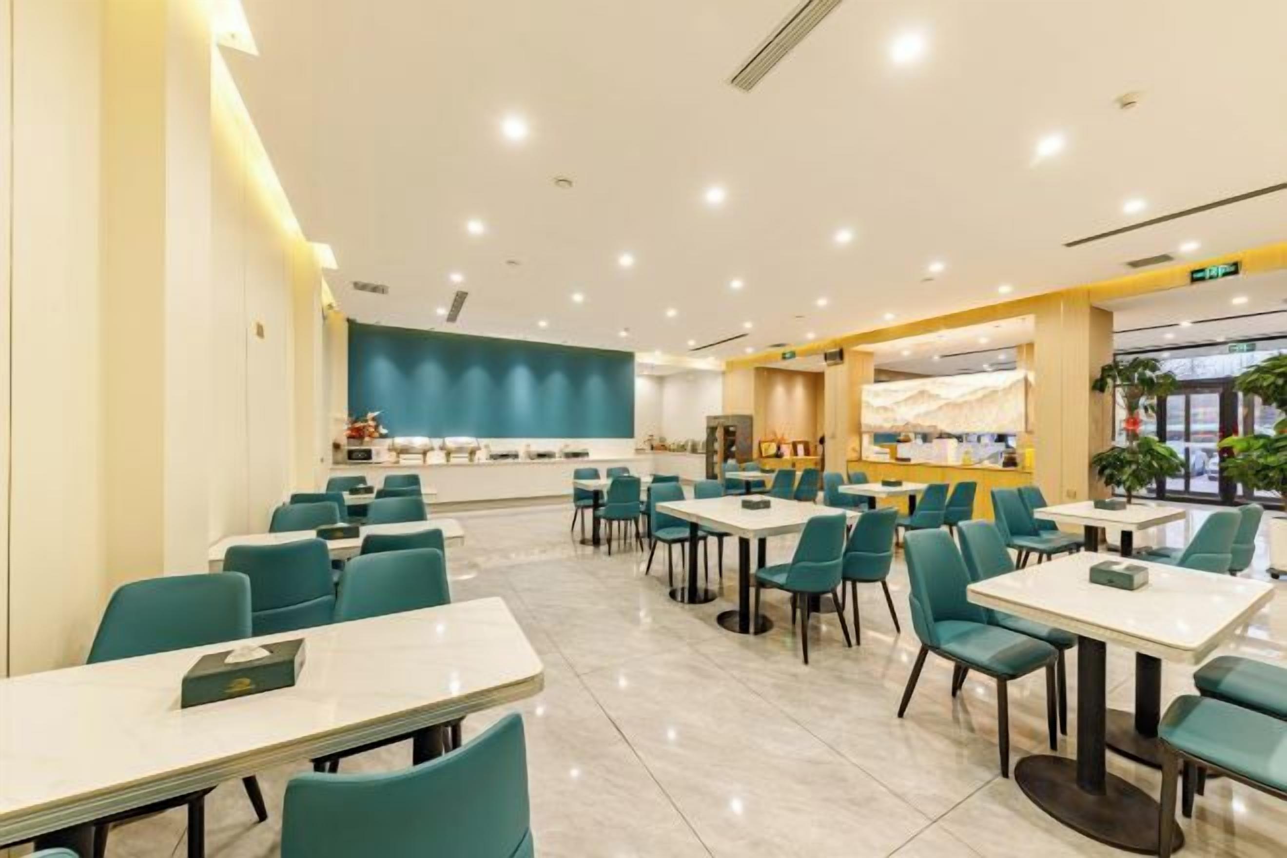 A spacious dining area with multiple tables and chairs, a counter, and a large window providing natural light.