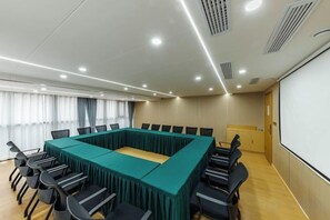 Ein Konferenzraum mit einem langen Tisch, Stühlen, einer Projektionsleinwand und einem Fenster mit Vorhängen.