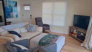 A living room with a sofa set, a grey armchair, a television, and a bookshelf. - Serene 3-bedroom waterfront newly renovated house, AC, Fast WiFi, Patio (White Marsh)