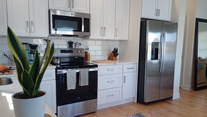 A modern kitchen with white cabinets, stainless steel appliances, a microwave, stove, and refrigerator. - Serene 3-bedroom waterfront newly renovated house, AC, Fast WiFi, Patio (White Marsh)