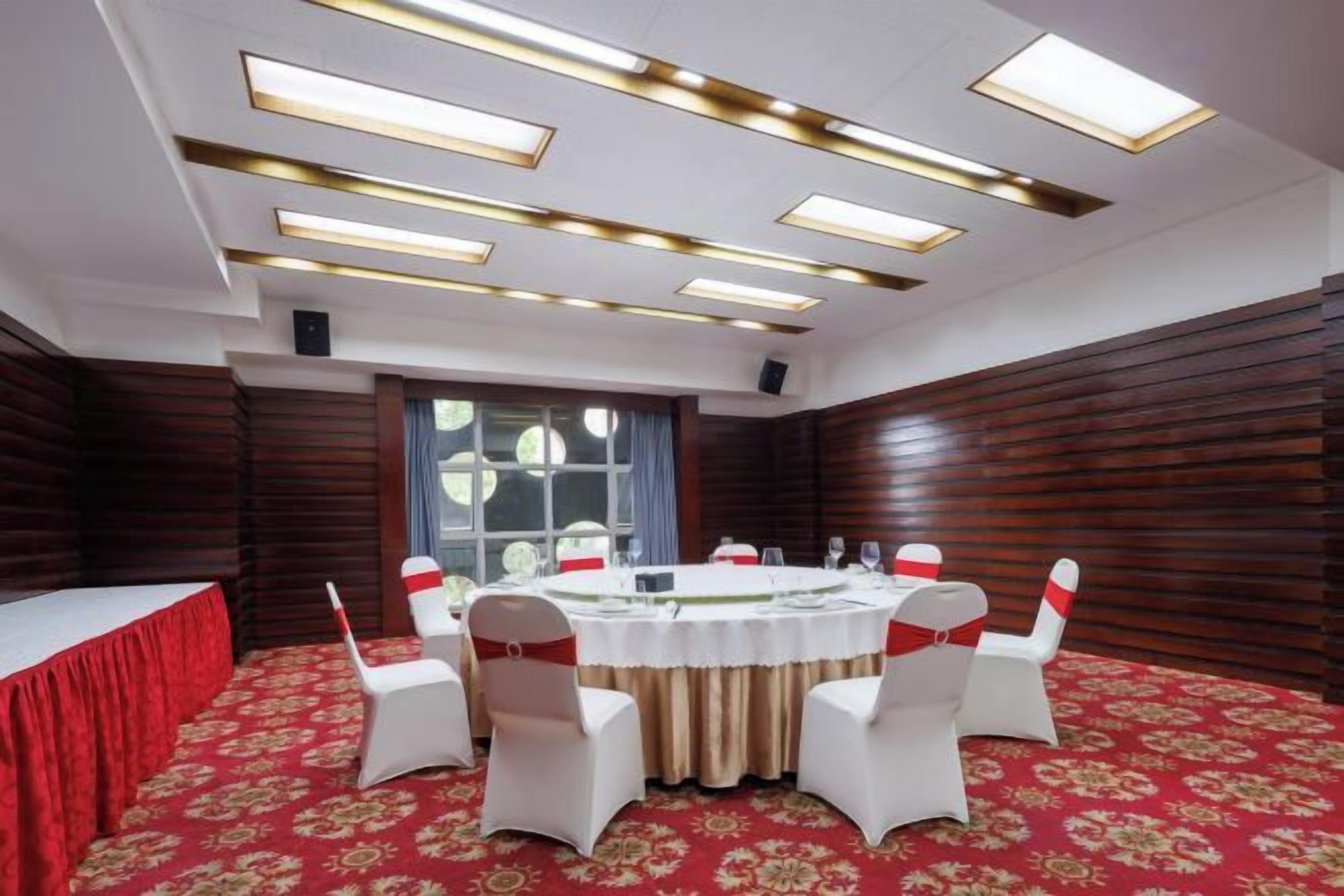 A conference room with a round table, white chairs, and a red carpet.