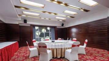 A conference room with a round table, white chairs, and a red carpet.