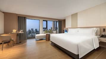 A hotel room with a large bed, a desk, and a view of the city.