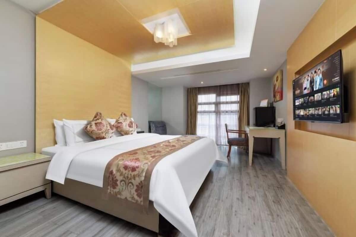 A hotel room with a bed, a desk, a television, and a large window.