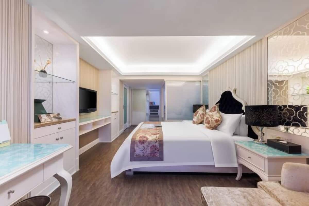 A modern bedroom with a bed, bedside tables, a TV, and a walk-in closet.